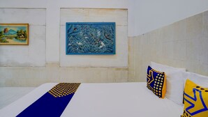 Habitación de hotel con cama, dos almohadas y dos cuadros en la pared.