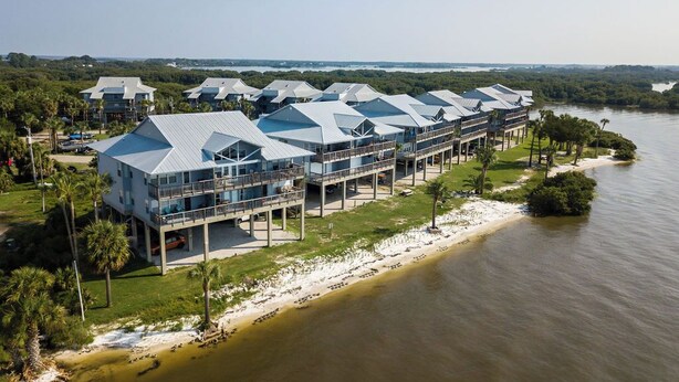 A waterfront hotel with multiple buildings featuring balconies and a pool area. - Fenimore Mill 1C - Pool and Beautiful Gulf Views! (Cedar Key)