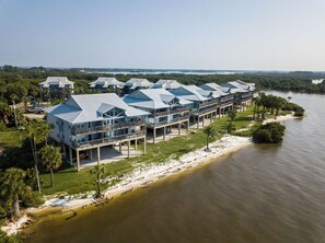 A waterfront hotel with multiple buildings featuring balconies and a pool area.