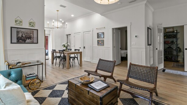Un salon spacieux avec une table basse en bois, un canapé bleu et un coin repas agrémenté d’un lustre.