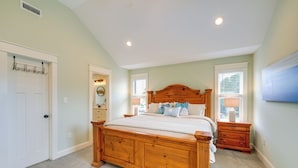 Une chambre à coucher avec un lit en bois, deux tables de chevet, une commode, un porte-manteau et une fenêtre avec des stores.