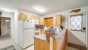 Cocina compacta con armarios de madera, refrigerador, microondas y cafetera.
