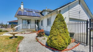 Una casa con paneles solares, un césped cuidado y un gran árbol de coníferas.