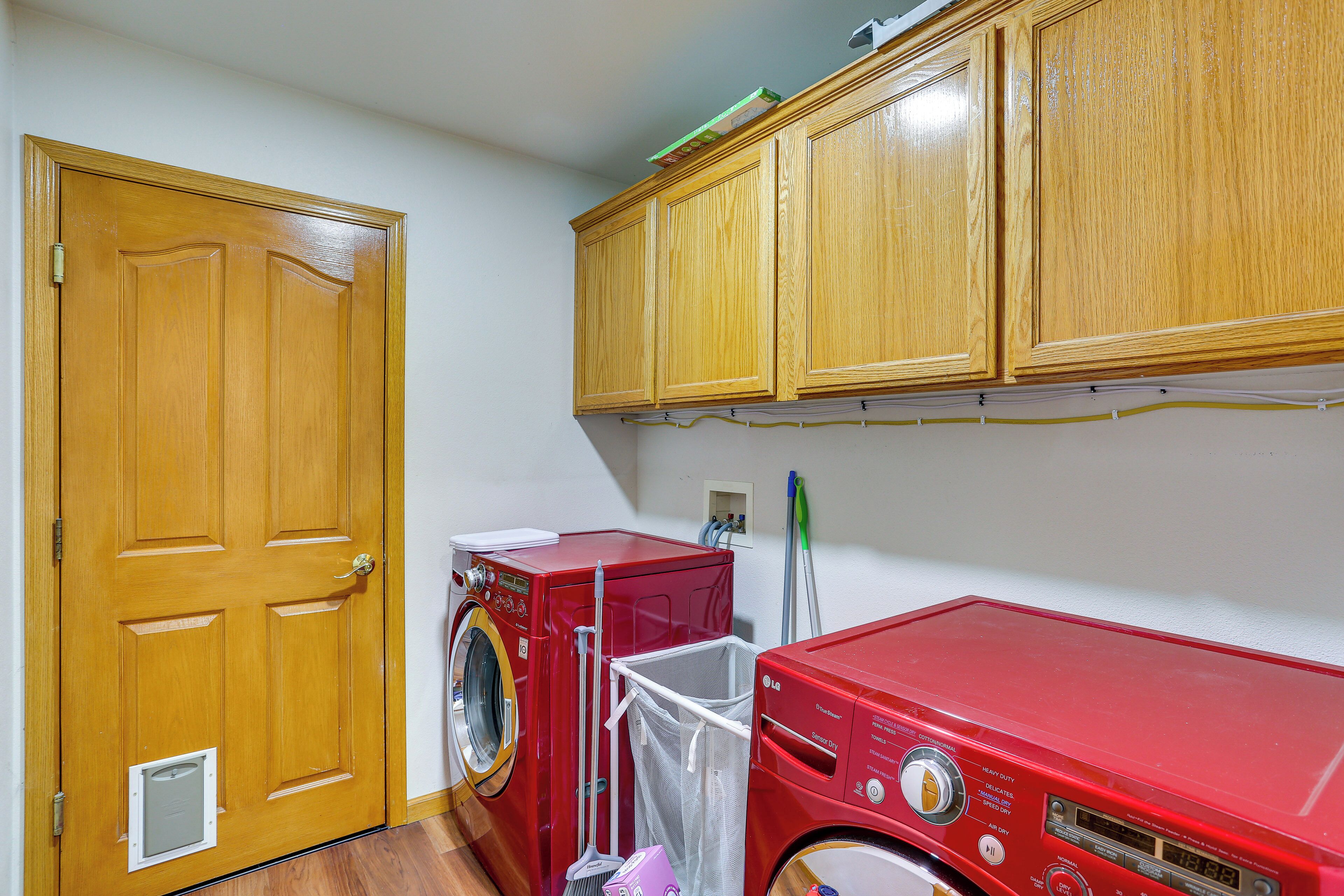 Une buanderie avec une porte en bois, un lave-linge rouge et un sèche-linge rouge.