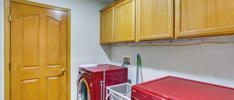 Une buanderie avec une porte en bois, un lave-linge rouge et un sèche-linge rouge.