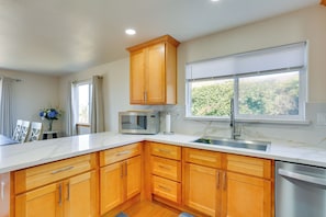 A modern kitchen with wooden cabinets, a built-in microwave, and a stainless steel dishwasher.
