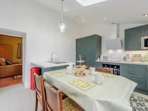 A compact kitchen with a central island, a dining table set for four, and a small seating area with a sofa.