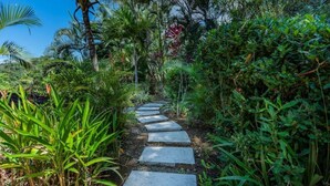 A stone pathway leading through a lush garden with various tropical plants and trees. - Villa Fortuna Best Piece of Heaven in Costa Rica (Provincia de Puntarenas)