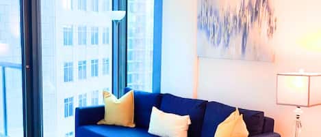 Un salon moderne avec un canapé bleu, une petite table sur laquelle est posée une plante et une lampe.