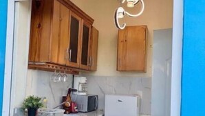 Une cuisine avec des meubles de rangement en bois, un four à micro-ondes, un réfrigérateur et un luminaire suspendu.
