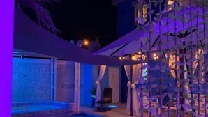 Un espace piscine avec vue sur un bâtiment, une chaise et une structure végétale décorative.