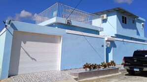 Un bâtiment à deux étages, avec une façade bleue, une porte de garage blanche et un camion noir garé devant.