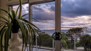 Ein Zimmer mit großem Fenster und Blick auf eine malerische Landschaft aus Meer und Bergen.