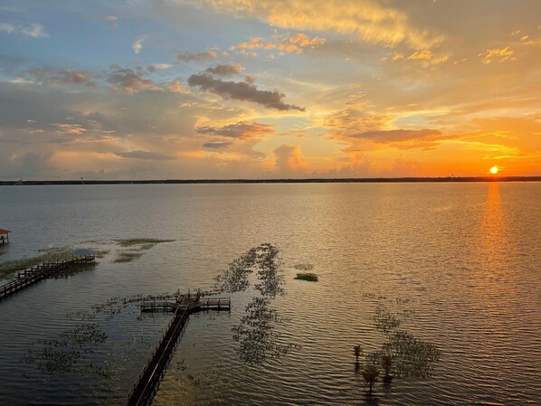 Un coucher de soleil sur une étendue d’eau calme, avec une jetée qui s’avance dans l’eau.