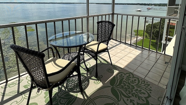 A balcony with a glass table and chairs, a ceiling fan, and a view of a lake with boats. - 2 Bed/2 Bath Condo - Close to Downtown Sebring & Racetrack (Sebring)