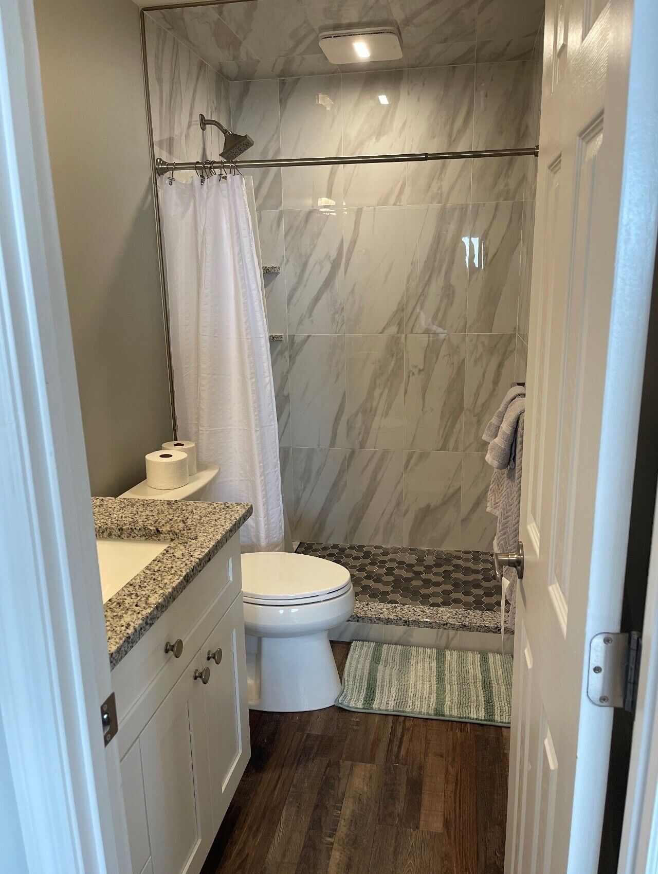 Une salle de bain équipée de toilettes, d’un lavabo, d’une douche et d’un mur en marbre.