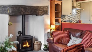 A cozy living room with a fireplace, leather sofa, and a kitchen in the background.