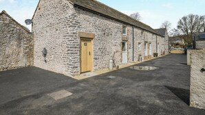 A stone building with a wooden door labeled "Dog Wash," a satellite dish, and a paved driveway.