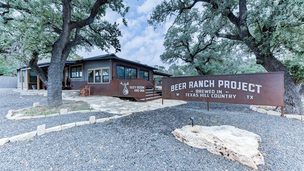 A rustic building with a sign reading "Beer Ranch Project Brewed in Texas Hill Country, TX." - Studio 1 at Beer Ranch Project. Walk to Wimberley Square. Unwind. Stay awhile. (Wimberley)