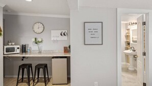 A modern kitchen with a microwave, a clock, and a framed quote on the wall. - Studio 1 at Beer Ranch Project. Walk to Wimberley Square. Unwind. Stay awhile. (Wimberley)