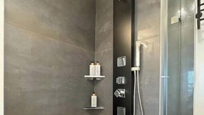 A modern shower area with a glass enclosure, a handheld showerhead, and a control panel. - Chic Downtown Salem 3 Bedroom w/ Parking (Salem)
