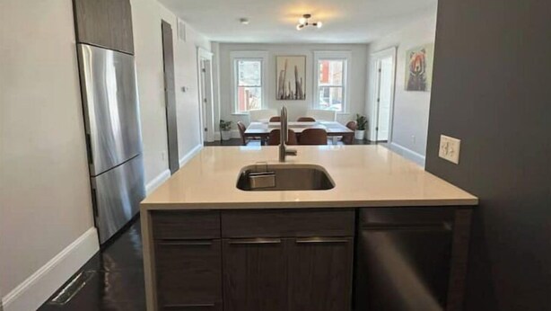 A modern kitchen with dark cabinetry, a stainless steel refrigerator, and a light-colored countertop. - Chic Downtown Salem 3 Bedroom w/ Parking (Salem)