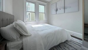 A bedroom with a bed, a window, and a wall-mounted artwork. - Chic Downtown Salem 3 Bedroom w/ Parking (Salem)