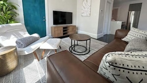 A modern living room with a sofa, a coffee table, and a TV on a wooden stand. - Chic Downtown Salem 3 Bedroom w/ Parking (Salem)