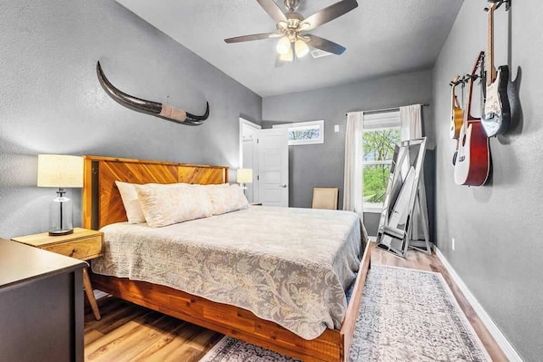 Ein Schlafzimmer mit einem hölzernen Bett, einem Deckenventilator und Gitarren an der Wand.