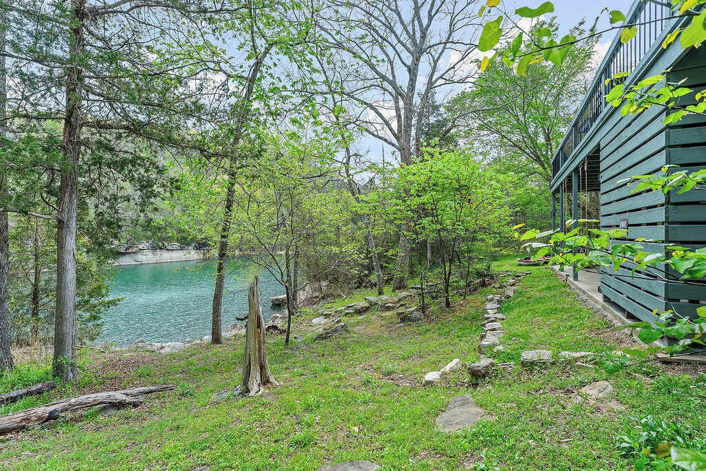 Paisaje natural con un cuerpo de agua, árboles y un edificio de madera.