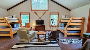 A cozy room with bunk beds, a television, a telescope, and a fireplace. - Lake Front | Fire Pit | Kayaks | Classic LakeCabin (Eureka Springs)