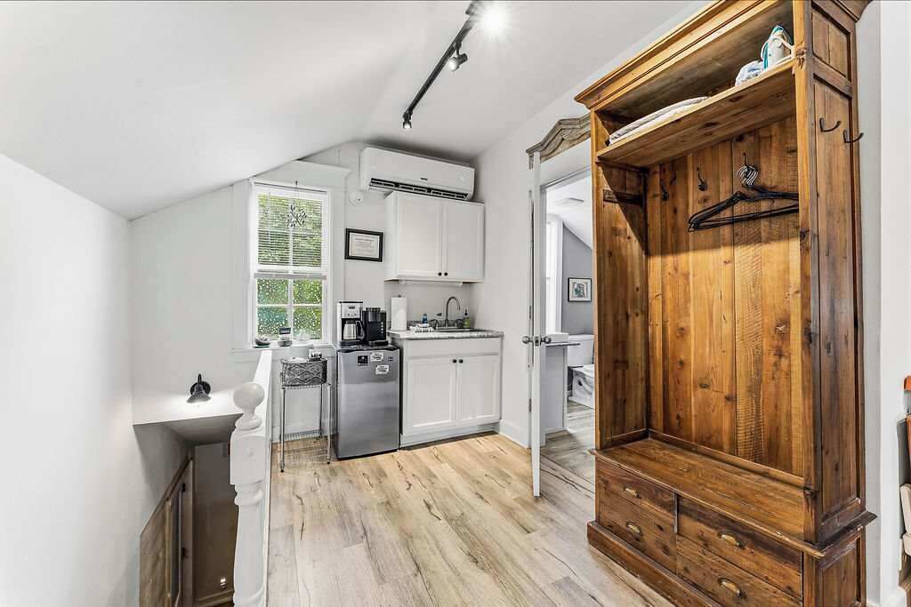 Een keuken met witte kasten, een houten kast en een hangrek.