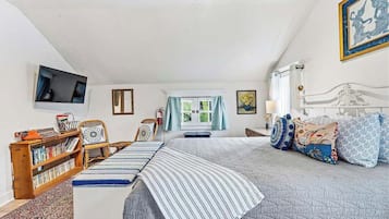 Une chambre à coucher avec un grand lit, une bibliothèque, un téléviseur et une fenêtre avec des rideaux.