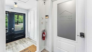 Entrada de hotel con puerta negra, extintor y puerta con la marca 'UPPERCASE lodging'.