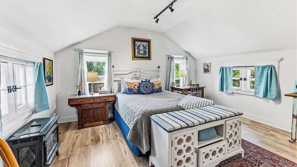 Un dormitorio con cama, cómoda, mesita de noche, ventana y radiador.