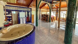 A spacious bathroom with a large bathtub, a shower area, and a vanity with a mirror. - Oceanfront Oasis with Meditation Tower & Pool (Hopeville)