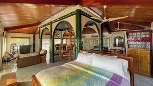 A spacious room with a large bed, a TV, and a dining area. - Oceanfront Oasis with Meditation Tower & Pool (Hopeville)