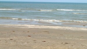 A beach with calm waves and a clear sky.