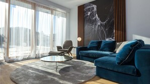 A modern living room with a blue sofa, a round coffee table, and a large abstract painting on the wall.