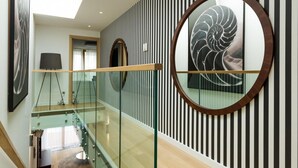 A modern interior with a glass railing, a spiral wall design, and a circular artwork.