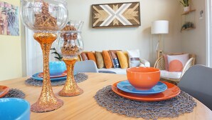 A dining table with a decorative centerpiece, a sofa with cushions, and a wall-mounted artwork. - Boho- Baha Retreat  Pool  7 min Beach & Airport (Nassau)