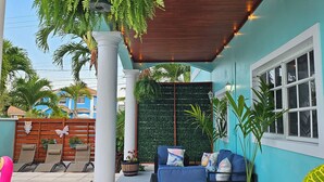 A covered patio area with a pool, lounge chairs, and a seating area with cushions. - Boho- Baha Retreat  Pool  7 min Beach & Airport (Nassau)