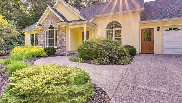 A two-story house with a stone facade, a front porch, and a garage. - Charming Flushing Cottage w/ Deck + Spacious Yard! (Flushing)