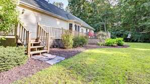 A house with a wooden deck, a stone pathway, and a well-maintained lawn. - Charming Flushing Cottage w/ Deck + Spacious Yard! (Flushing)