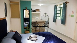 Een slaapkamer met een bed, bureau en kitchenette.
