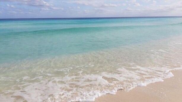 Een strand met helder turquoise water en een zandstrand.