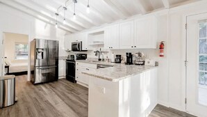 A modern kitchen with white cabinets, stainless steel appliances, and a granite countertop. - Lazy Creek Cove Cottage w EV Plug! (Chapin)