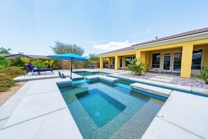 A swimming pool with a sunken center, surrounded by a patio area with lounge chairs and a barbecue grill.