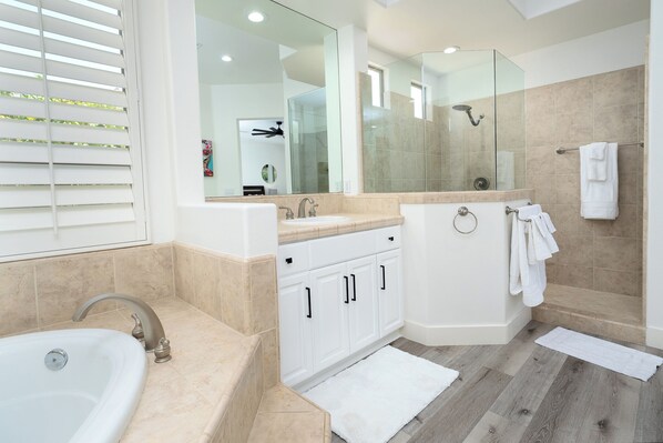 A modern bathroom with a large mirror, two sinks, a bathtub, and a shower. - Luxurious 5BR Resort Style Home w/ Pool & Spa (Indio)