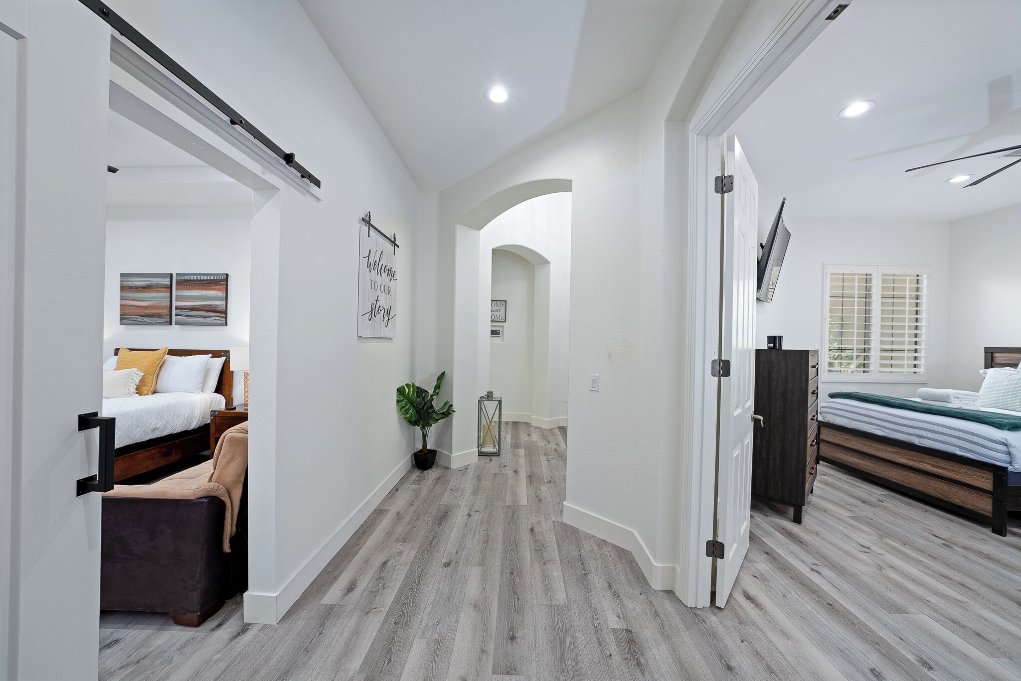 Un dormitorio moderno con suelo de madera, una cama, una mesita de noche y una planta en maceta.